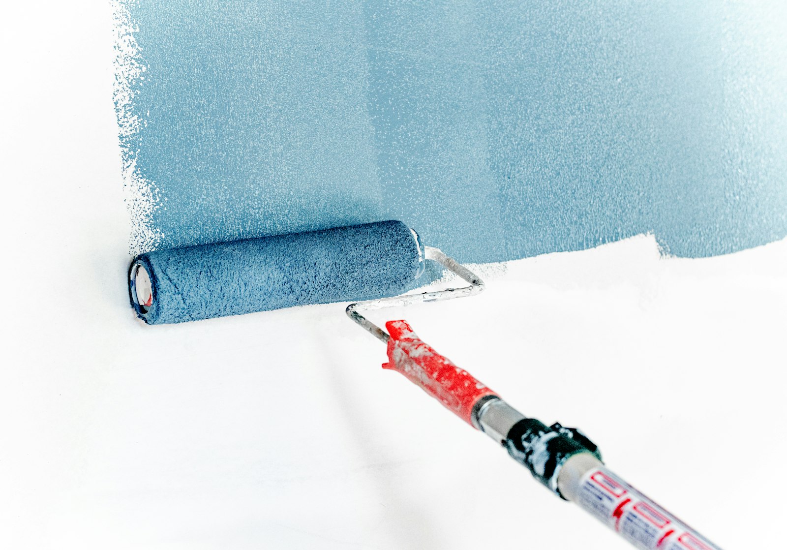 Detalle macro de rodillo aplicando pintura azul premium